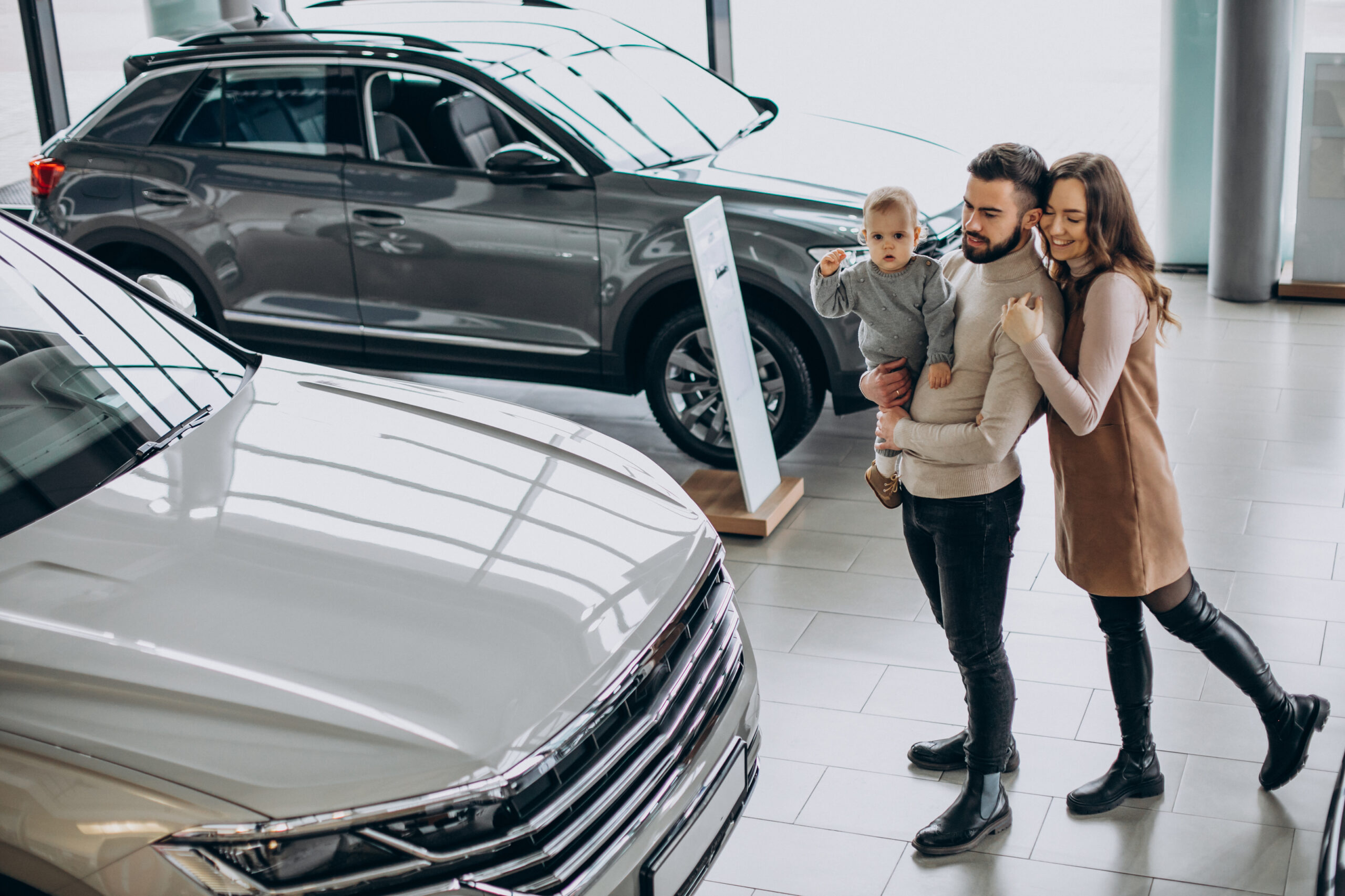 Family with toddler girl choosing a car in a car showroom